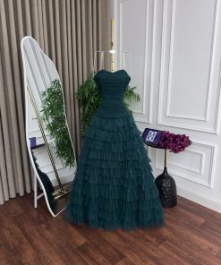 Alternative view of فستان سهرة فاخر بتصميم أنيق ولون أخضر بترولي عميق، يتميز بقصّة كورسيه محكمة تبرز جمال القوام وتمنح إطلالة راقية. الجزء العلوي مصنوع بتفصيلات درابية ناعمة تضيف لمسة أنثوية، مع تنورة واسعة متعددة الطبقات من التول الخفيف تمنح الفستان حركة وانسيابية جذابة. اختيار مثالي للمناسبات الرسمية والسهرات الفاخرة.