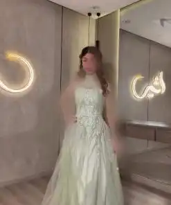 فستان سهرة أخضر فستقي بتصميم هالتر وتطريز راقٍ