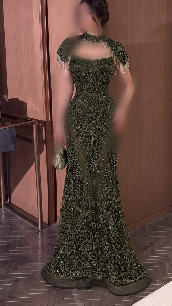 فستان سهرة زيتوني طويل بتصميم ياقة عالية وكاب قصير مزين بالشراشيب مع تطريز فاخر