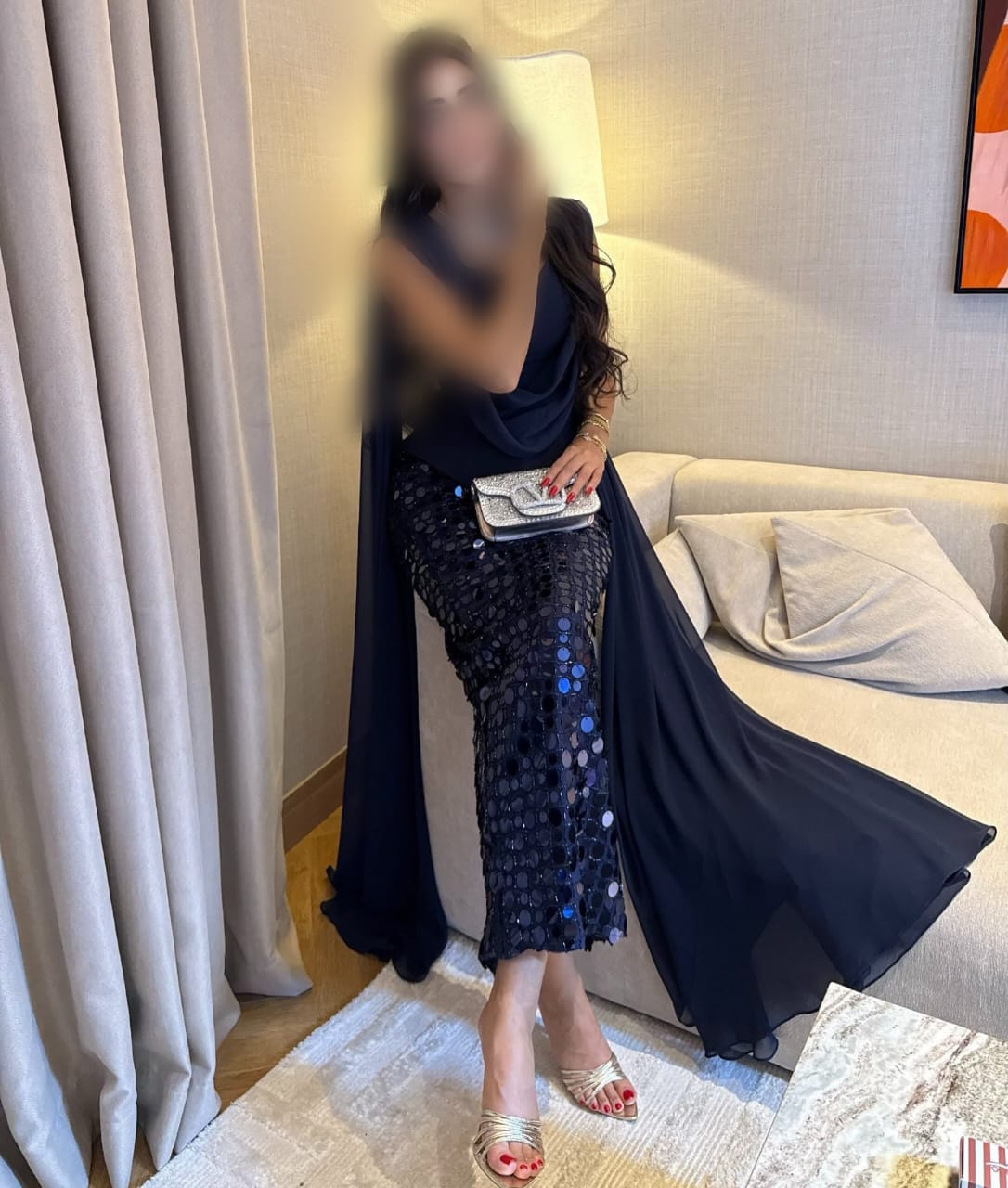 فستان سهرة كحلي داكن طويل بشال خلفي متصل وتنورة مزينة بترتر دائري براق.